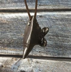 a small metal object hanging from a chain on a wooden surface with wood planks