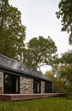 a small stone house in the middle of a forest with trees and grass around it