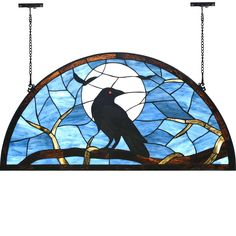 a stained glass window with a bird perched on a branch in front of the moon