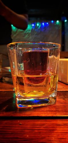 a glass filled with liquid sitting on top of a wooden table