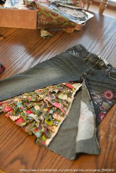 several pairs of jeans sitting on top of a wooden table