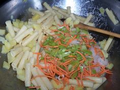 carrots, onions and celery being cooked in a wok