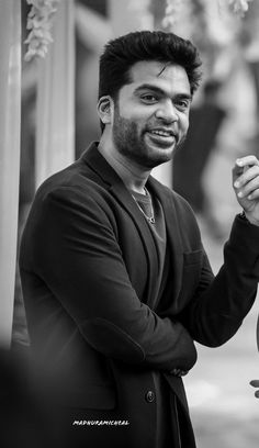 a black and white photo of a man holding something in his hand while standing outside