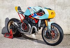 a blue and yellow motorcycle parked next to a cement wall with a red tire guard