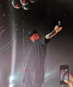 a man holding a microphone up to the side of his head while standing on stage