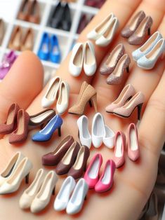 there are many miniature shoes in the palm of someone's hand, all different colors and sizes