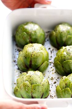 a white dish filled with brussel sprouts covered in seasoning