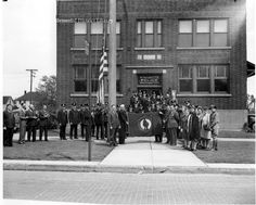 an old black and white photo of people standing in front of a building with flags