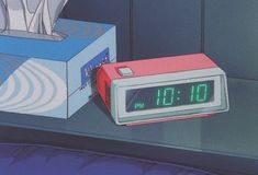 an alarm clock sitting on top of a box next to a tissue dispenser