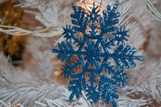 a blue snowflake ornament hanging from a christmas tree