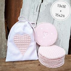 pink and white heart appliques are sitting on a wooden table next to a bag