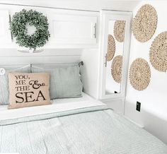 a bed with a pillow that says you me and the sea on it next to a wreath