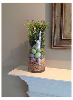 a vase filled with eggs and flowers on top of a mantle