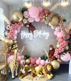 a birthday decoration with balloons and animals on the floor next to a wall that says happy birthday