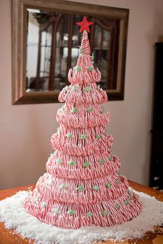 a pink christmas tree made out of cupcakes on top of a wooden table