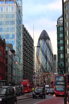 cars, buses and double decker buses on a city street with skyscrapers in the background