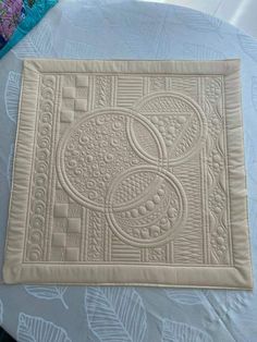 a close up of a quilted place mat on a table with flowers and leaves