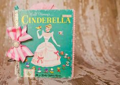 an old children's book with a pink bow on it sitting on a wooden table