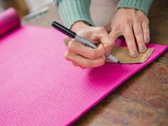 a woman is writing on a pink mat