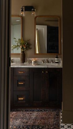 a bathroom with two sinks, mirrors and a rug on the floor in front of it