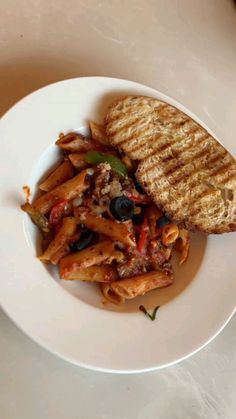 a white plate topped with pasta and an open pita bread on top of a table