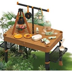 an outdoor picnic table with various items on it and plants in the backgroud