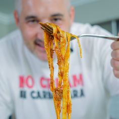 a man holding a fork full of cheesy pasta on it's side