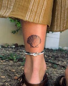 a woman's foot with a small shell tattoo on her left leg and ankle