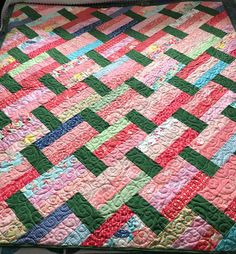 a colorful quilt is laying on top of a tablecloth that looks like it has been made from strips of fabric