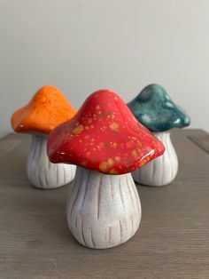 three ceramic mushrooms sitting on top of a wooden table