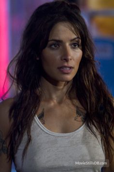 a close up of a person wearing a tank top and looking at the camera with a serious look on her face