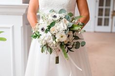 a bridal holding a bouquet of white flowers and greenery