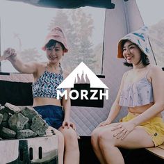 two young women sitting next to each other in front of a camper with the word morzh on it