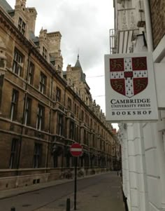 the cambridge book shop sign is posted on the side of the building next to the street