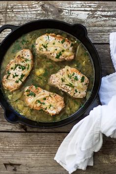 chicken and vegetable stew in a cast iron skillet on a wooden table with napkins