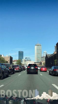 cars are driving down the street in boston, massachusetts on a sunny day with skyscrapers in the background