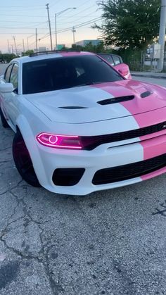 a white and pink car parked in a parking lot