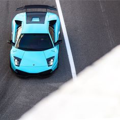 a blue sports car driving down a race track