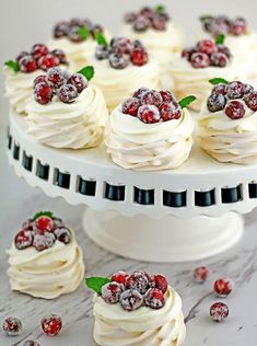 a cake with white frosting and raspberries is on a platter surrounded by cranberries