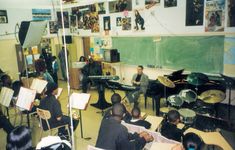 a group of people playing instruments in front of a class room full of musicians and students