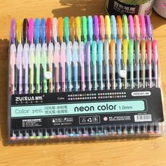 a bunch of different colored pens sitting on top of a wooden table