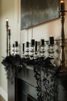 black candles are lined up on the mantle