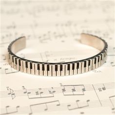 a bracelet with piano keys on top of sheet music