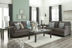 a living room with two couches and a coffee table in front of the windows