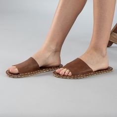 Introducing the Lion Barefoot Slide Sandals the perfect addition to your summer wardrobe. Handmade in Turkey with 100% natural materials, these sandals are crafted with a natural leather upper and a water buffalo leather sole, ensuring maximum comfort and breathability for your feet. With a wider toe box, your toes have enough room to spread and relax, promoting a more natural gait and posture. The "zero-drop" non-elevated heel helps maintain proper posture as well. Available in sizes ranging fr Brown Flat Heel Sandals For Beach, Leather Sole Slip-on Mules For Vacation, Beach Flip Flops With Leather Footbed, Leather Slippers With Cushioned Footbed For Vacation, Summer Vacation Huarache Sandals With Rubber Sole, Comfortable Beach Footbed Sandals With Single Toe Strap, Brown Sandals With Woven Sole And Flat Heel, Brown Flat Heel Slippers With Cork-bed Midsoles, Brown Single Toe Strap Slippers For Beach