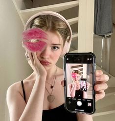 a woman taking a selfie in front of a mirror with a pink doughnut