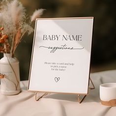 a baby name sign sitting on top of a table next to a vase with flowers