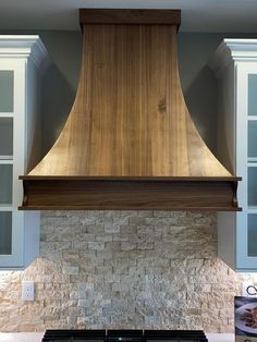 a stove top oven sitting inside of a kitchen under a wooden hood over it's burner