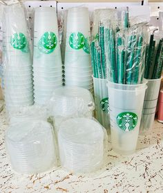 starbucks cups are lined up on the counter with plastic straws in each cup and wrapped in plastic bags