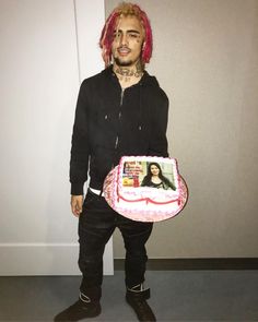 a man with pink hair holding a cake